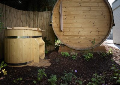 Moderne Garten-Sauna mit rundem Tauchbecken und natürlichem Sichtschutz aus Bambus