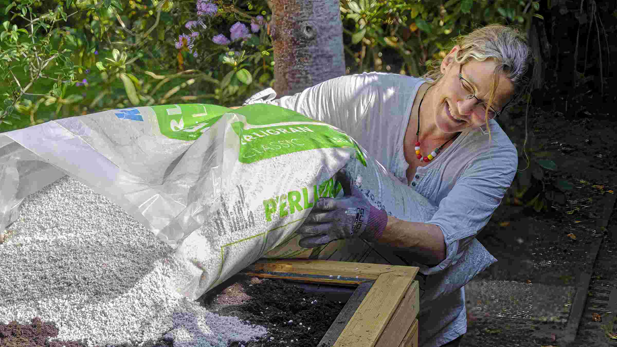 Vorbereitung der Bepflanzung eines Holz-Mülltonnenschranks mit Substrat und feuchtigkeitsspeicherndem Granulat